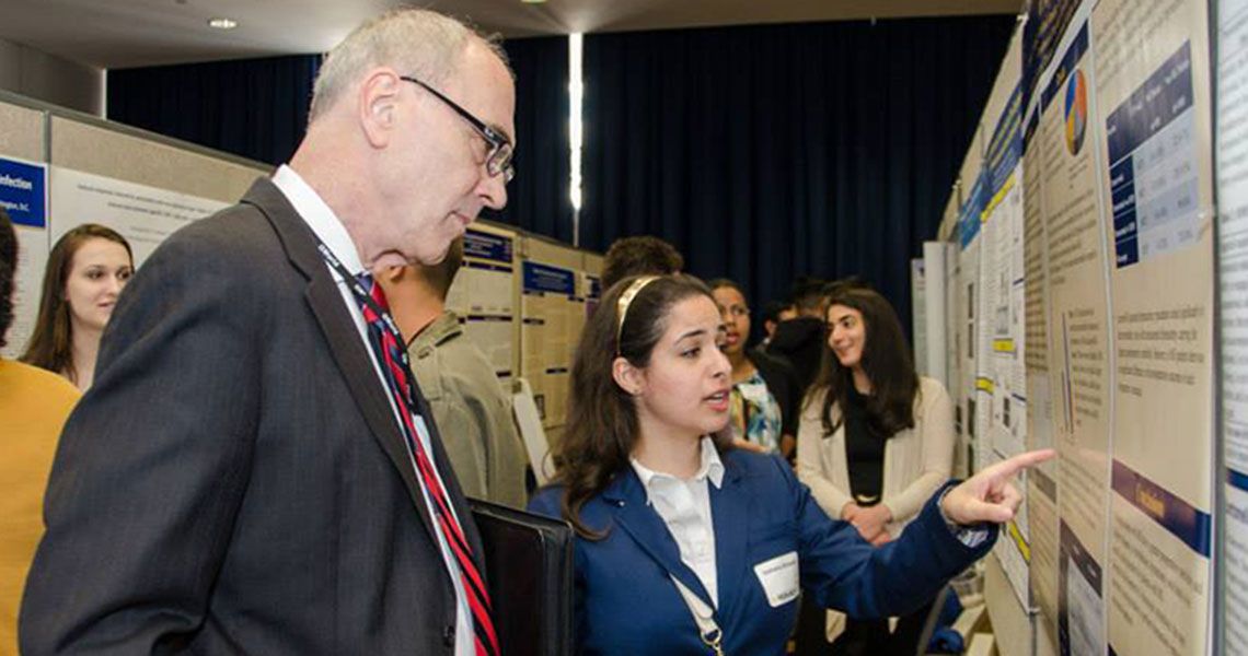 Jumana Alshaikh showing Robert Miller her research poster