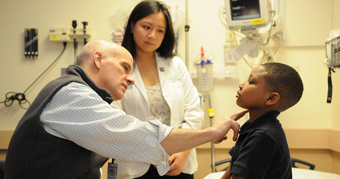 Dr. Stephen Teach checking the pulse of a child patient