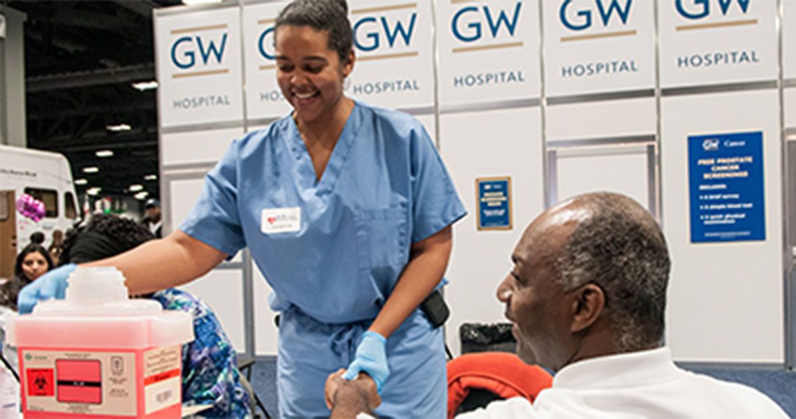 A GW Hospital medical volunteer worker with a community member at expo booth