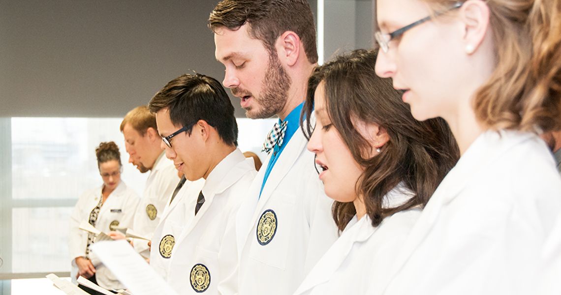 Health sciences students reading papers and wearing their white coats