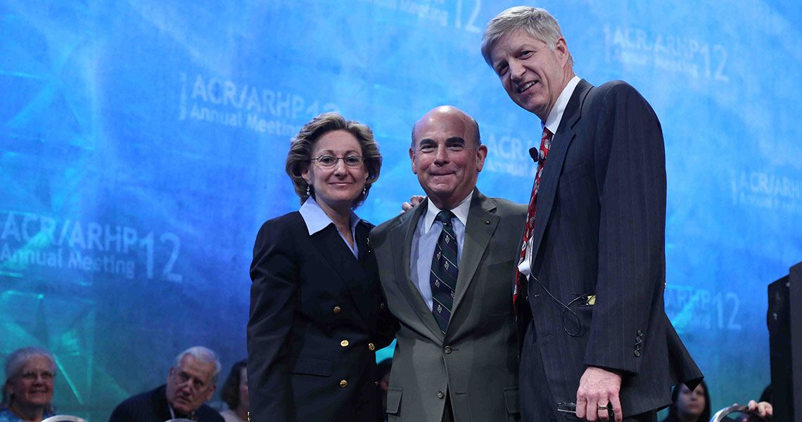 Dr. Stuart Kassan posing with two colleagues in front of a blue wall