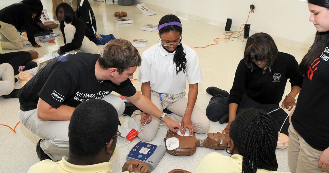 Students gathered around a practice dummy to train CPR