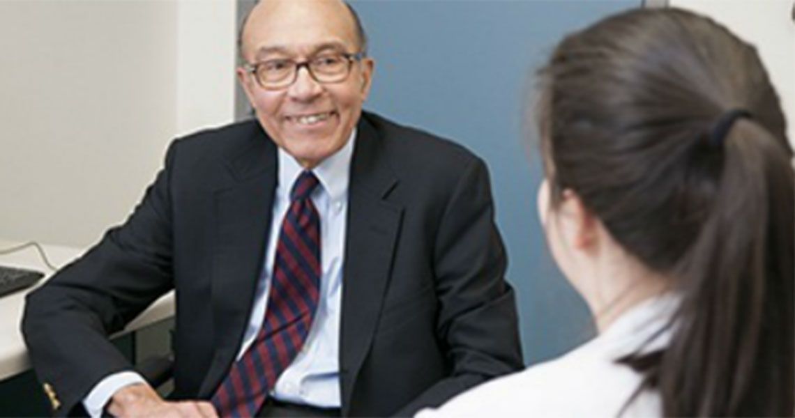 A man smiling at a student in conversation