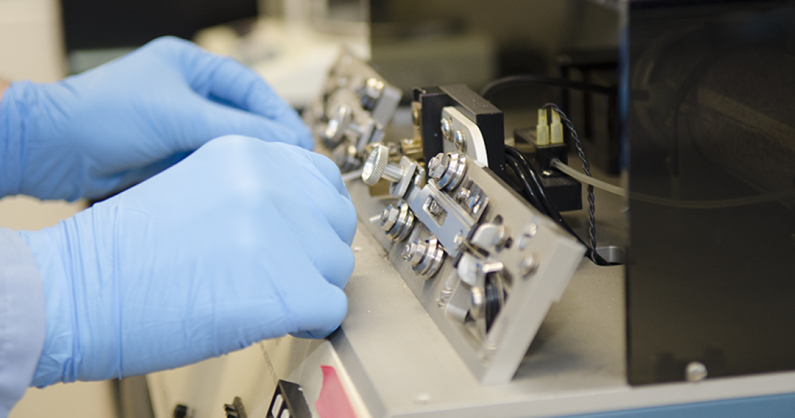 Two gloved hands are shown with research equipment
