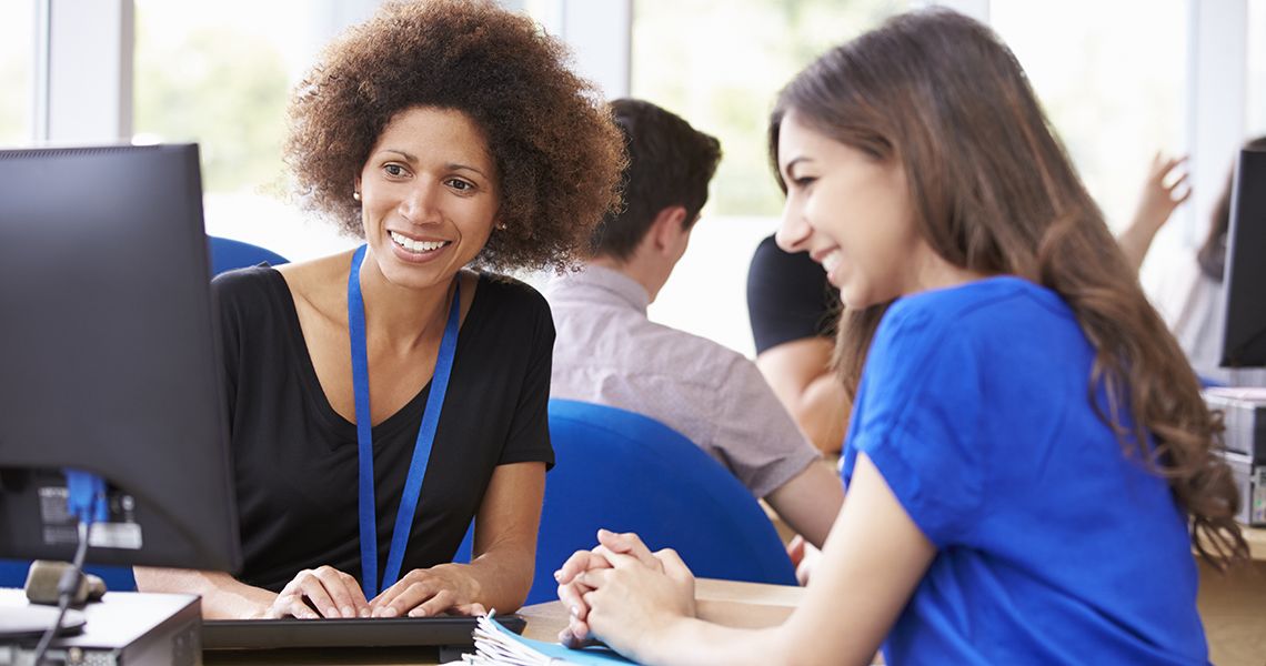 student and student support person sitting smiling and looking at a computer together