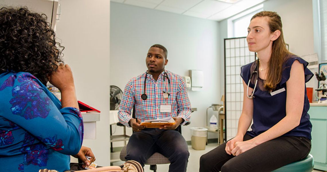 Two medical students listen to a patient