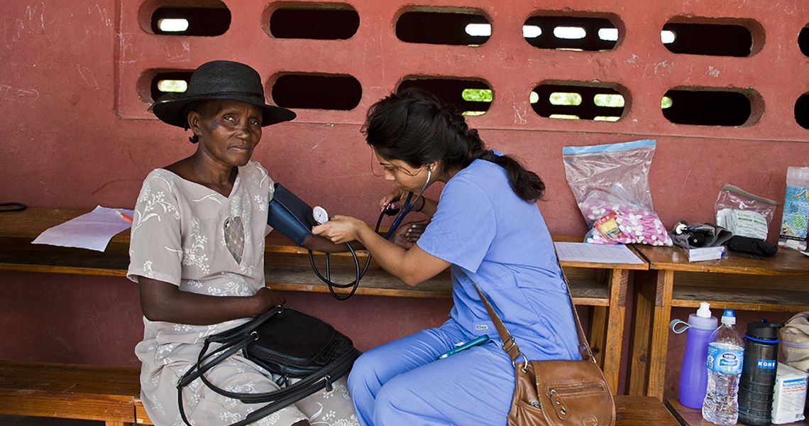 Med student taking a patient's blood pressure in Haiti