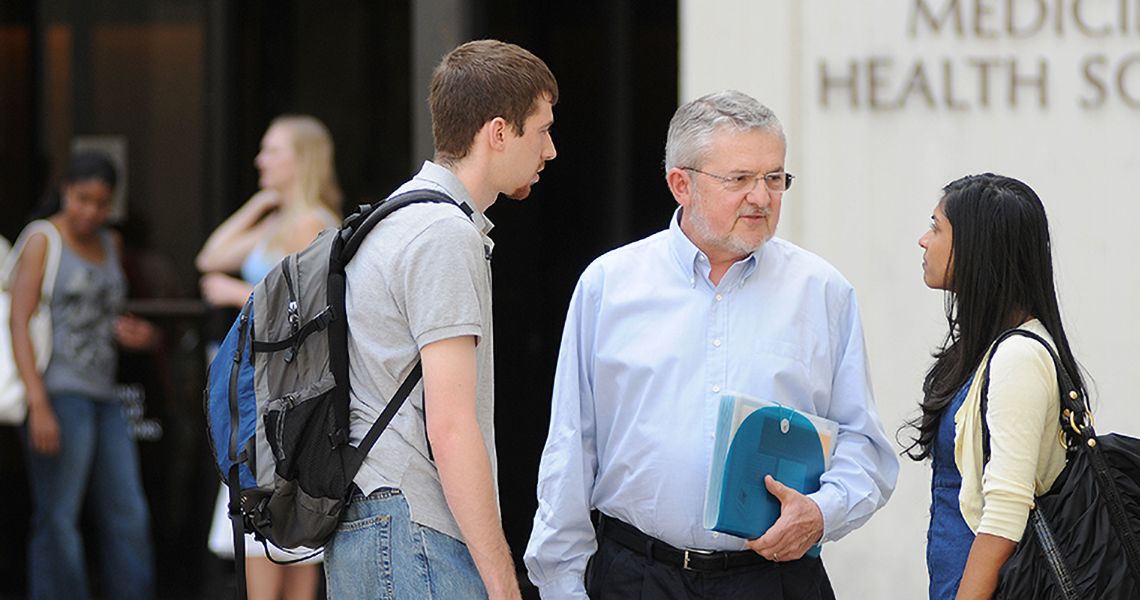 Professor talking to students outside of Ross Hall