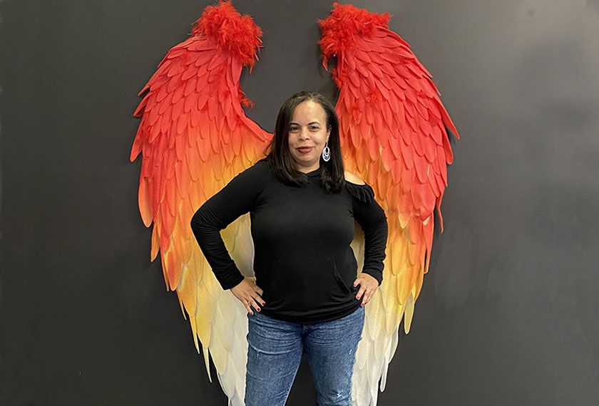 Carmen Sessions standing in front of fire-colored wings