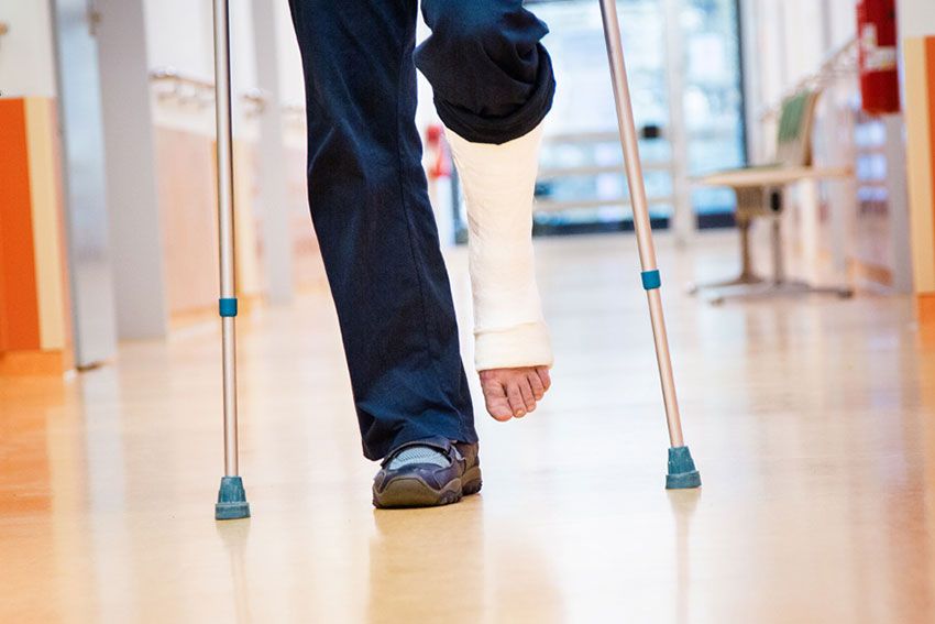 A patient walking with crutches and a cast around their left leg