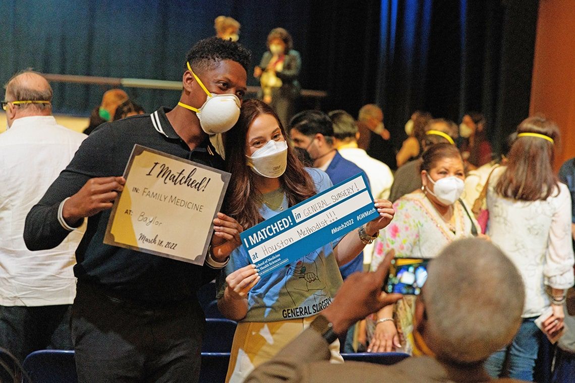 Two medical students pose for photos with their match envelopes