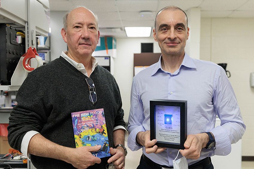 Drs McCaffrey and Kasimov stand with a book and a research award, respectively
