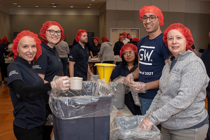 Participants with hairnets at a food station at the Rise Against Hunger event