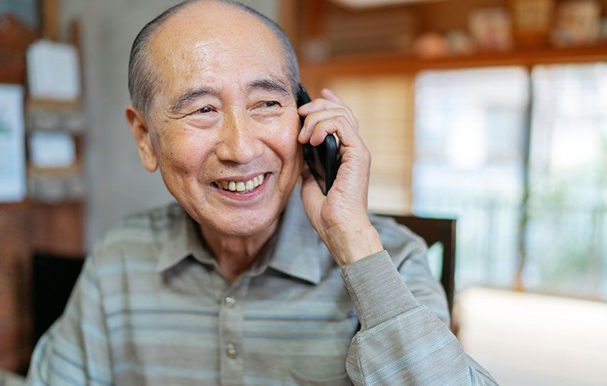 Elderly man smiling and speaking on an iPhone