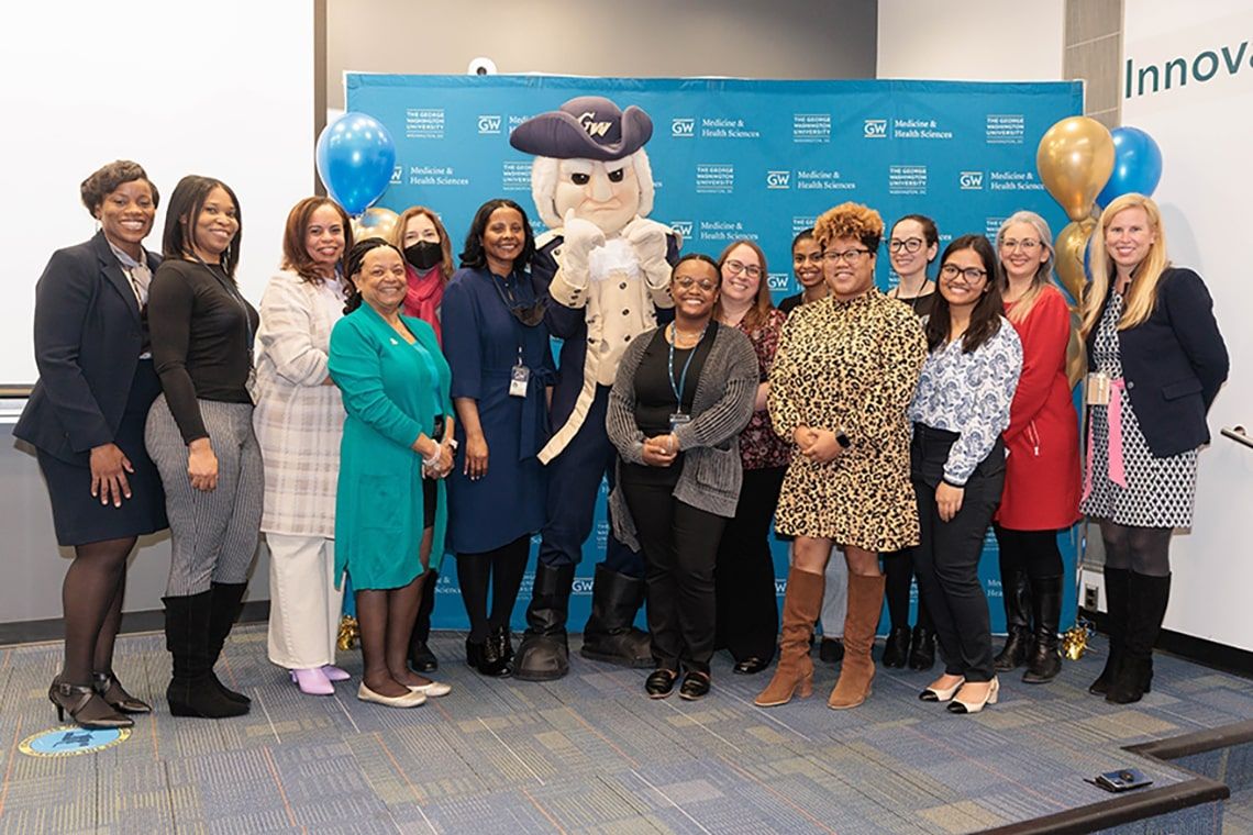 The employee appreciation committee stand with the GW mascot 