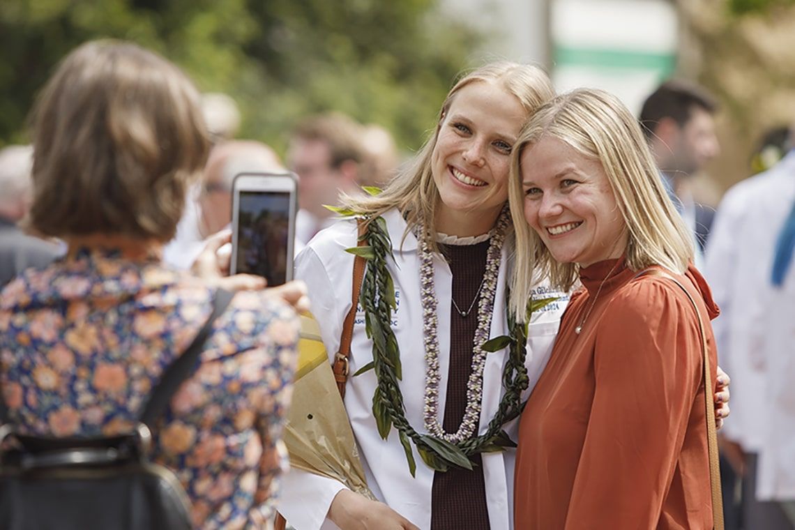 A student poses with a friend outside after the class of 2024 White Coat ceremony