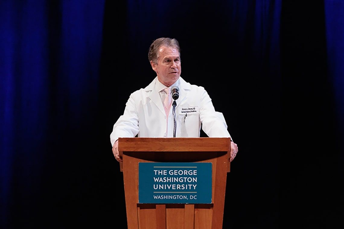 Dean Simons speaking from a podium at the class of 2024 White Coat ceremony