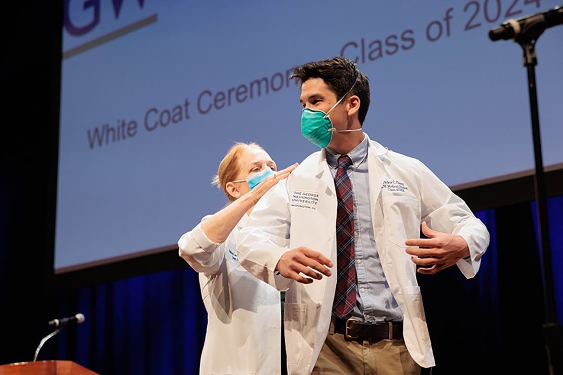 Student donning a white coat at the class of 2024 White Coat ceremony