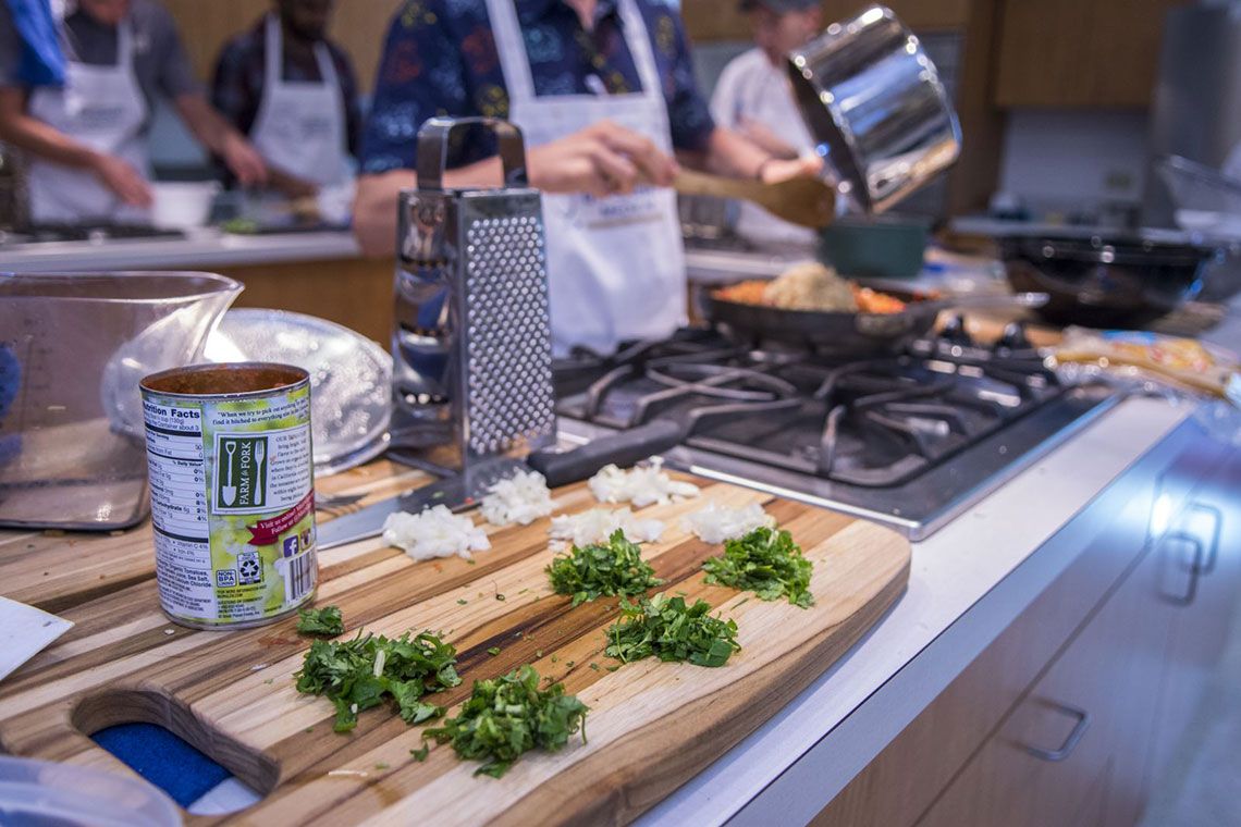 Chopped onion and cilantro on a cutting board next to a stovetop