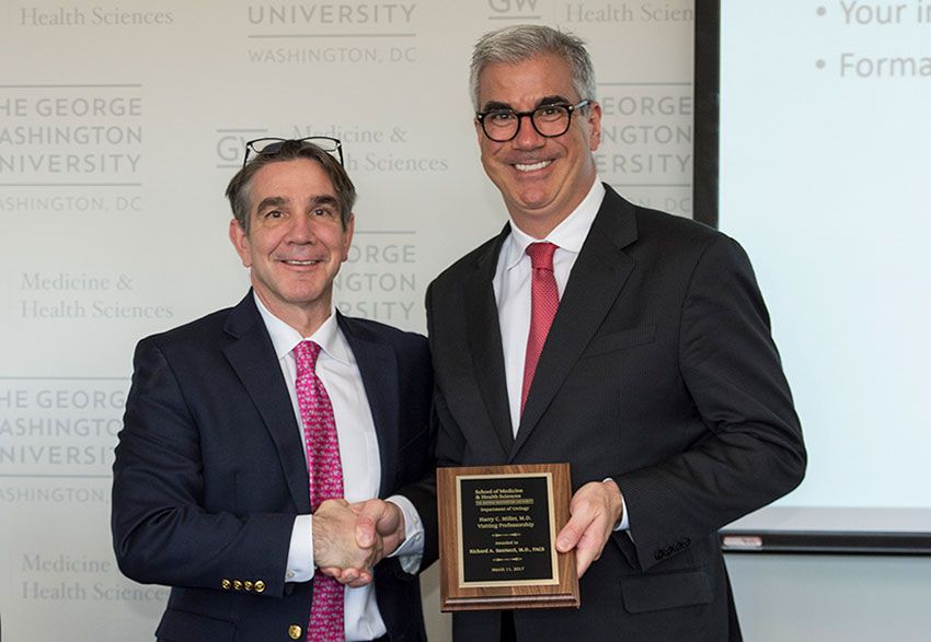 Two men standing at a podium holding a plaque