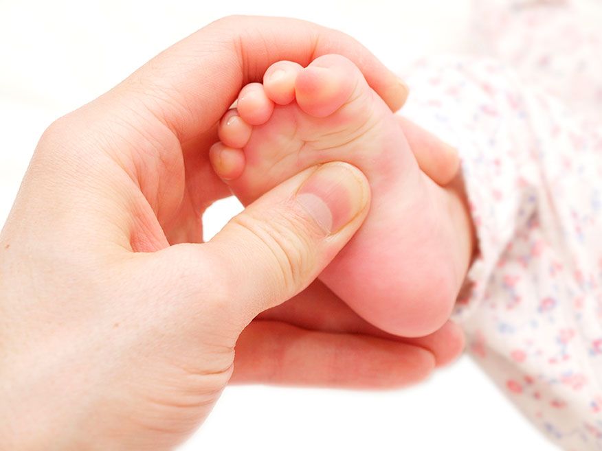 A hand holding a baby's foot