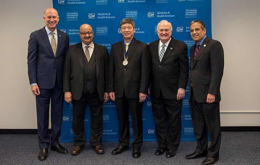 Edward Seto wearing a medal and standing among GW medical faculty