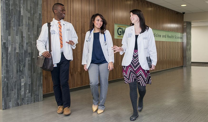 Three people walk down a hallway