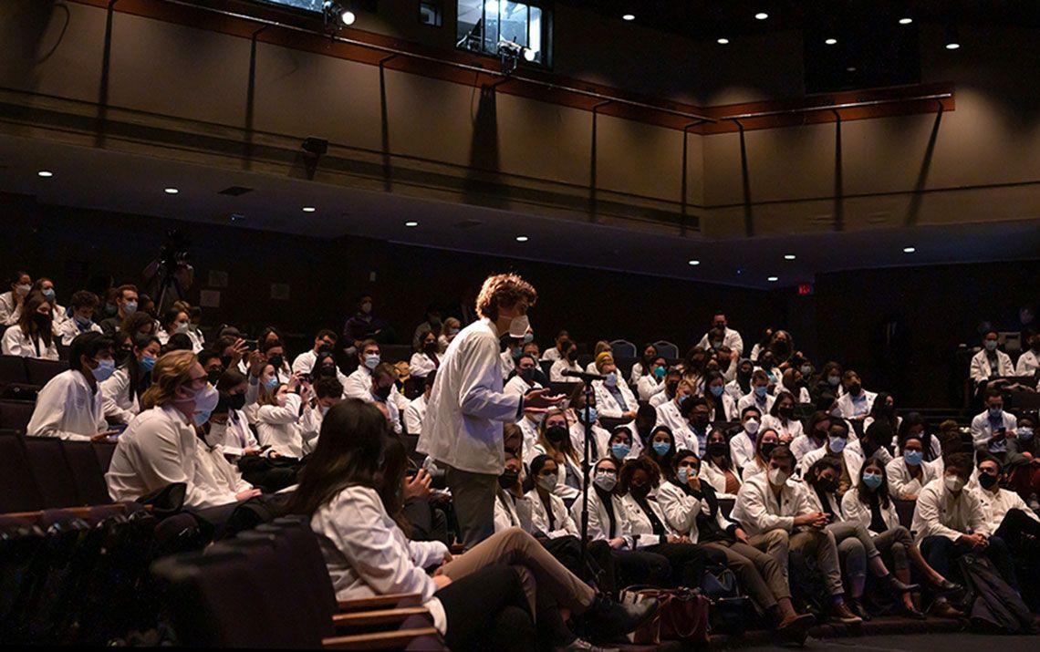 A First-year MD student speaking into a microphone among an audience