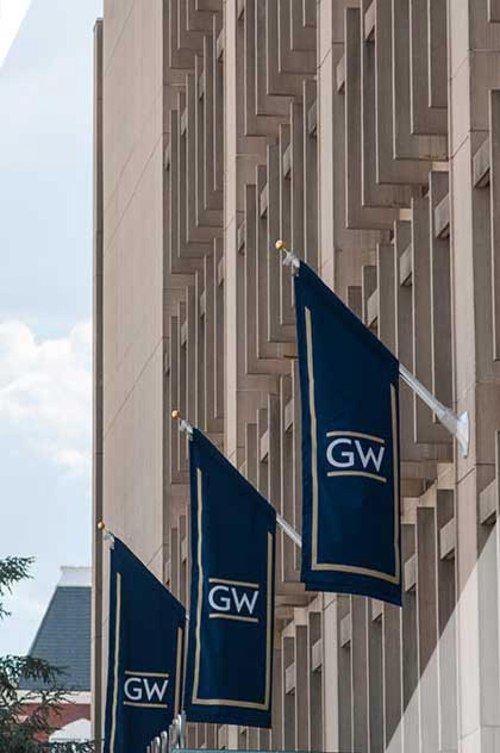Three "GW" flags hang from a building