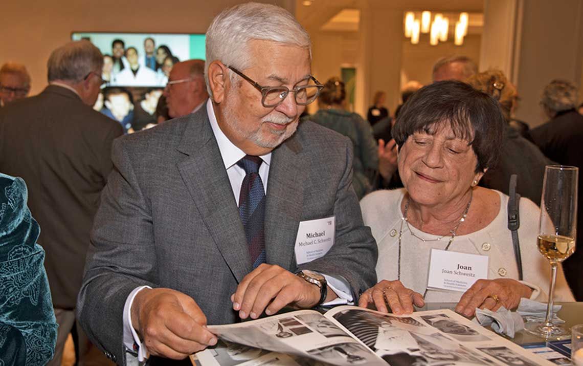 Michael Schweitz, MD ’72, BA ’69, and Joan Schweitz page through an old yearbook