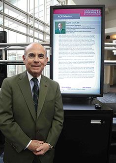 Dr. Stuart Kassan standing in front of a monitor showing information about him