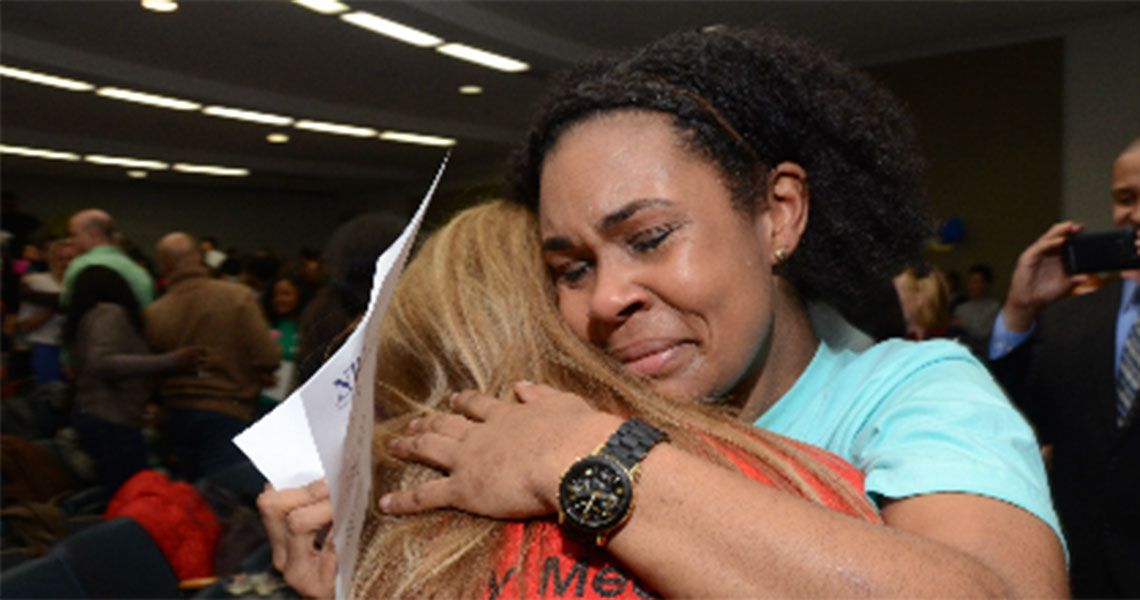 A medical student hugging a woman while holding her match day results