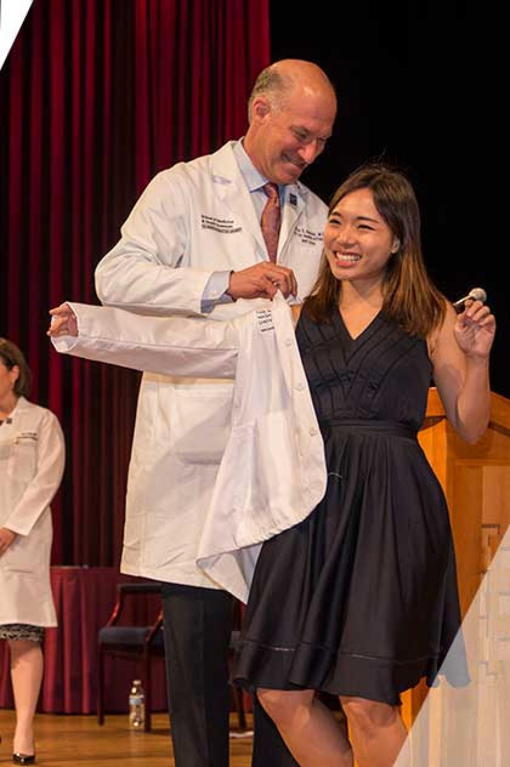 A woman receives her coat during a white coat ceremony