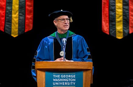 Dr. Jeffrey Akman wearing regalia and speaking from a podium