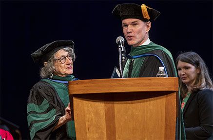 Two people in regalia standing at a podium