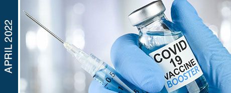 A gloved hand holding a COVID-19 vaccine vial and syringe | "April 2022"