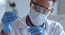 Scientist wearing a mask and putting a pipette in a tube