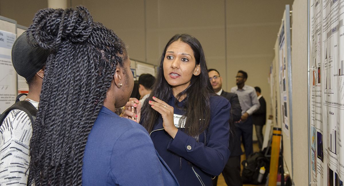 A woman speaks to another woman in a hallway