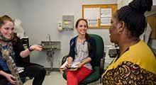 Three women are shown inside a patient room at a health clinic