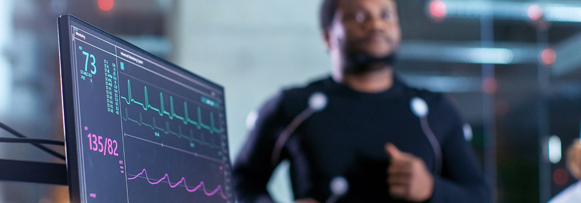 Monitor with heart rate data with a person running on a treadmill in the background