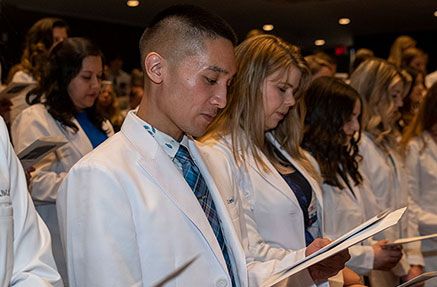 Physician Assistant studies students wearing white coats and reciting an oath