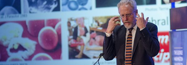 someone speaking at a lectern in front a large screen