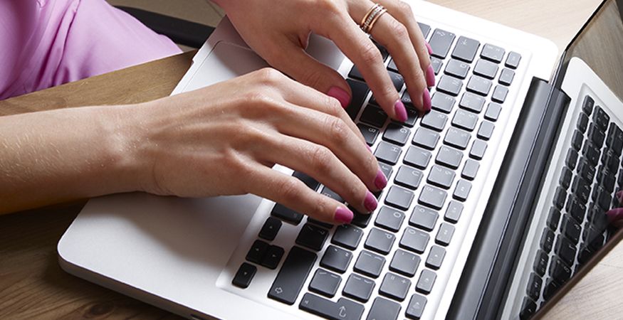 Close up of fingers typing on a laptop