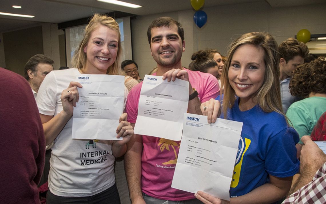 students smiling and holding their match day letters