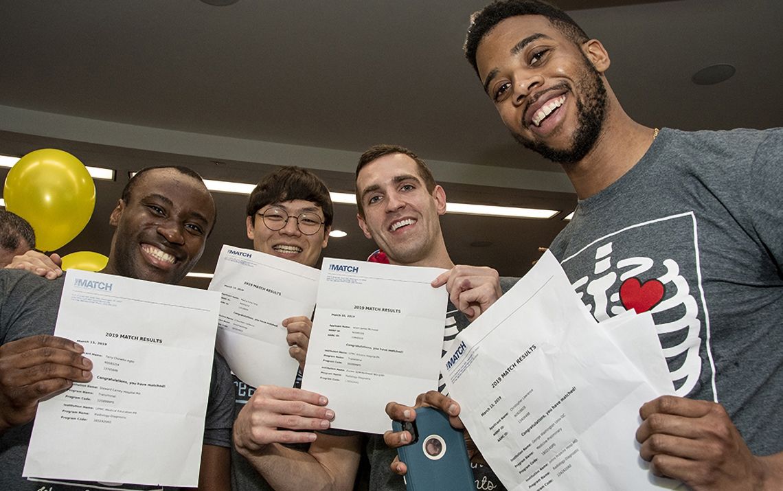 students smiling and holding match letters