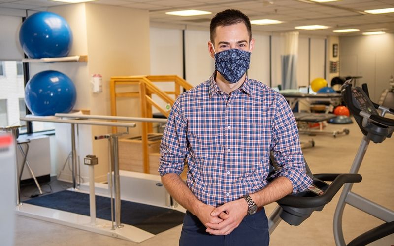 Michael Taber wearing a mask and standing in the PT clinic