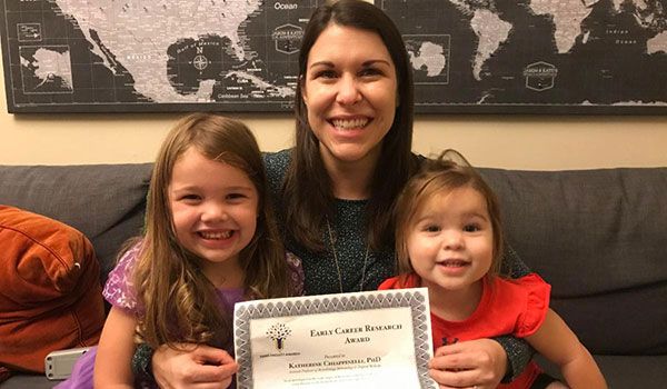 Dr. Katherine Chiappinelli posing with a certificate and her children