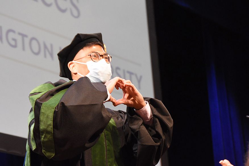 Student making heart sign on stage