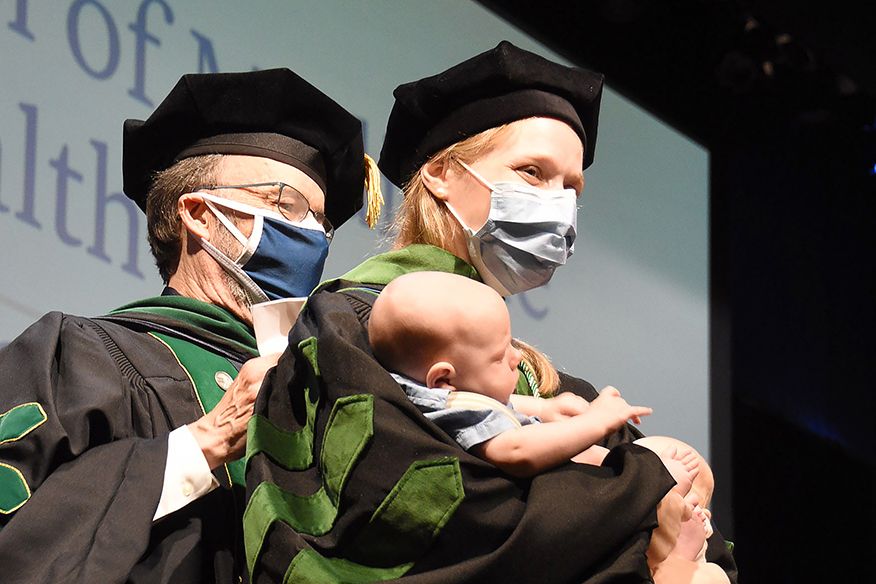 Student with baby getting hooded
