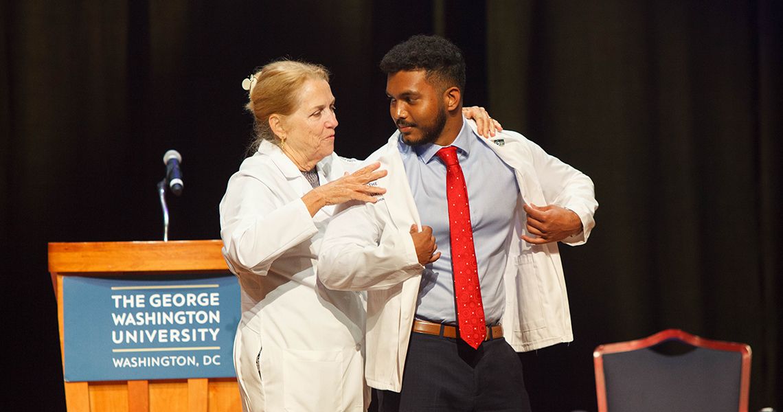 Dean Bass held student with white coat